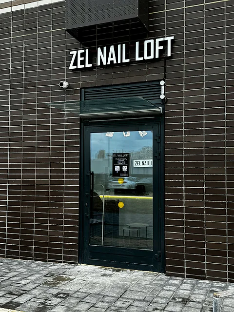 Вход в студию Zel Nail Loft: тёмный кирпичный фасад и стеклянная дверь