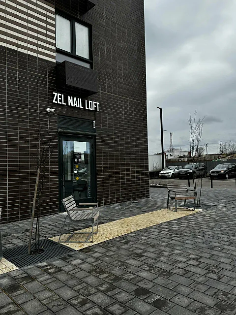 Вход в студию Zel Nail Loft с улицы: тёмный кирпичный фасад и световая вывеска