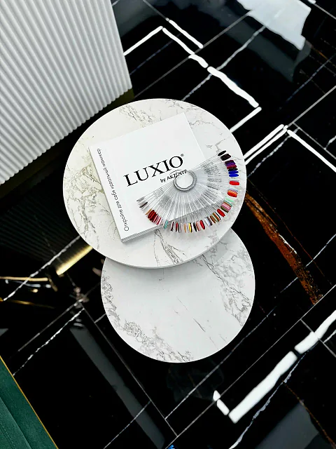 Мраморный столик с каталогом LUXIO и веером образцов оттенков на чёрном полу