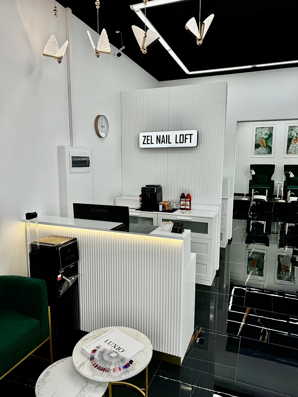 Ресепшн Zel Nail Loft: белая рифлёная стойка, вывеска студии, светильники-бабочки